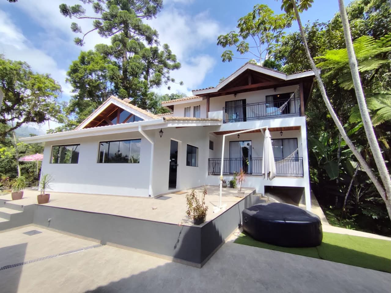 A mesma casa concluída, com pintura branca, telha cerâmica, varandas e terraço