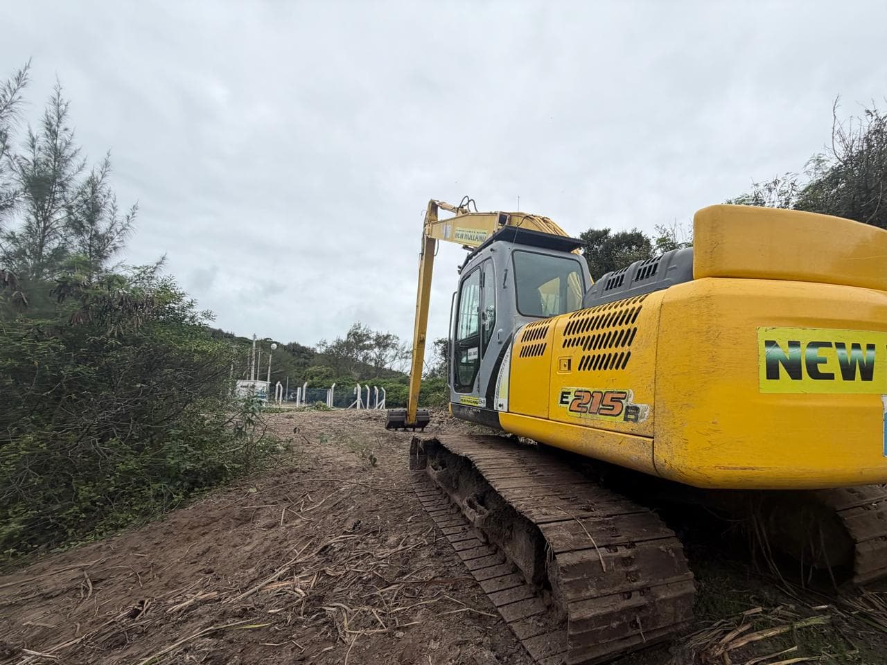 Escavadeira hidráulica de alcance longo posicionada na faixa de terreno já limpa